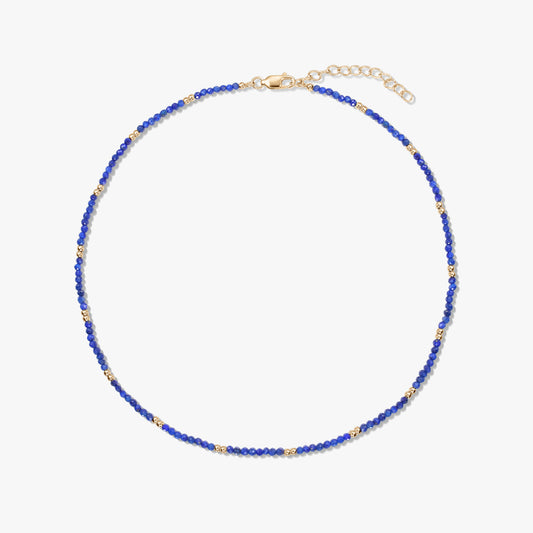 Kecses lápisz lazuli gyöngysor apró, aranyozott sterling ezüst díszítésekkel és állítható delfinkapoccsal, fehér háttéren.